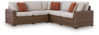 Outdoor sectional sofa with beige cushions, brown wicker frame, and rust accent pillows