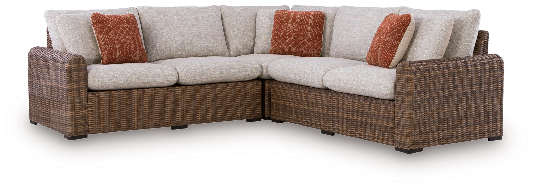 Outdoor sectional sofa with beige cushions, brown wicker frame, and rust accent pillows