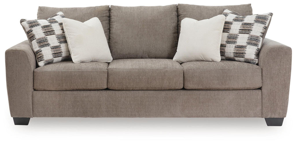 Sofa sleeper, beige upholstery with plaid and white throw pillows.