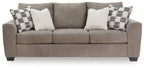 Sofa sleeper, beige upholstery with plaid and white throw pillows.