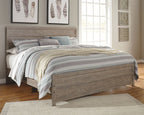 Gray panel bed with low footboard, dressed with layered patterned bedding