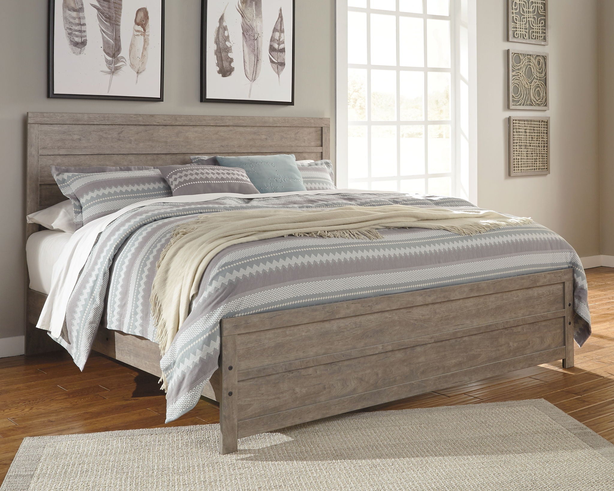 Gray panel bed with low footboard, dressed with layered patterned bedding