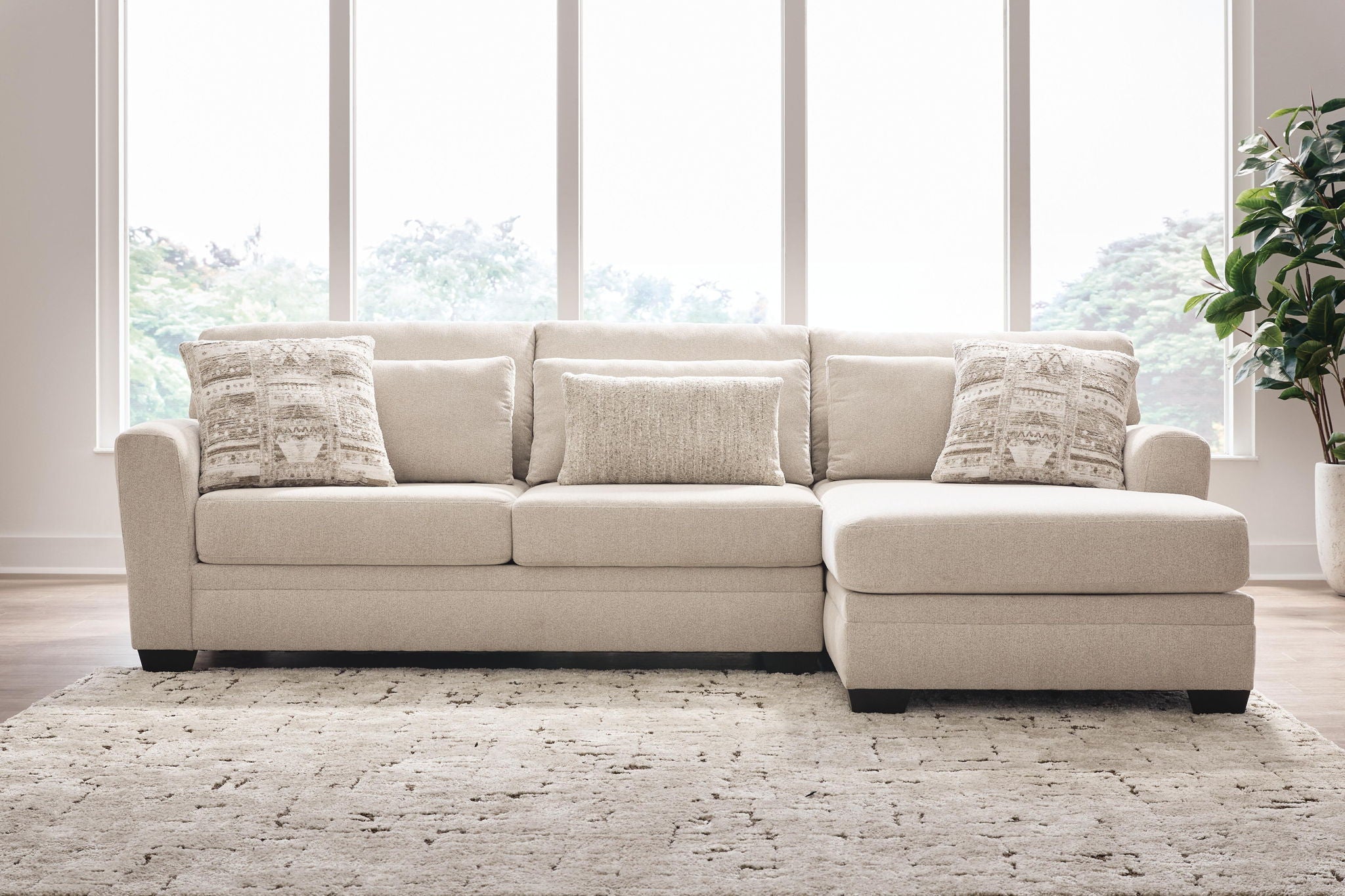 Light beige sectional sofa with chaise, tufted cushions and two patterned accent pillows