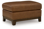 Saonara amber ottoman with tufted top, faux leather-look, studded trim, dark wooden legs