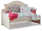 Chipped white twin day bed with gray tufted headboard and light quilt, pink throw and pillows