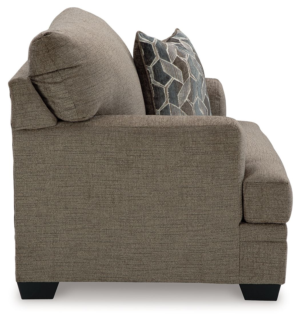 Brown chair-and-a-half armchair with geometric throw pillow and thick arm padding