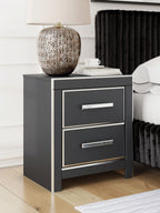 Black two-drawer night stand with two silver bar pulls beside a bed