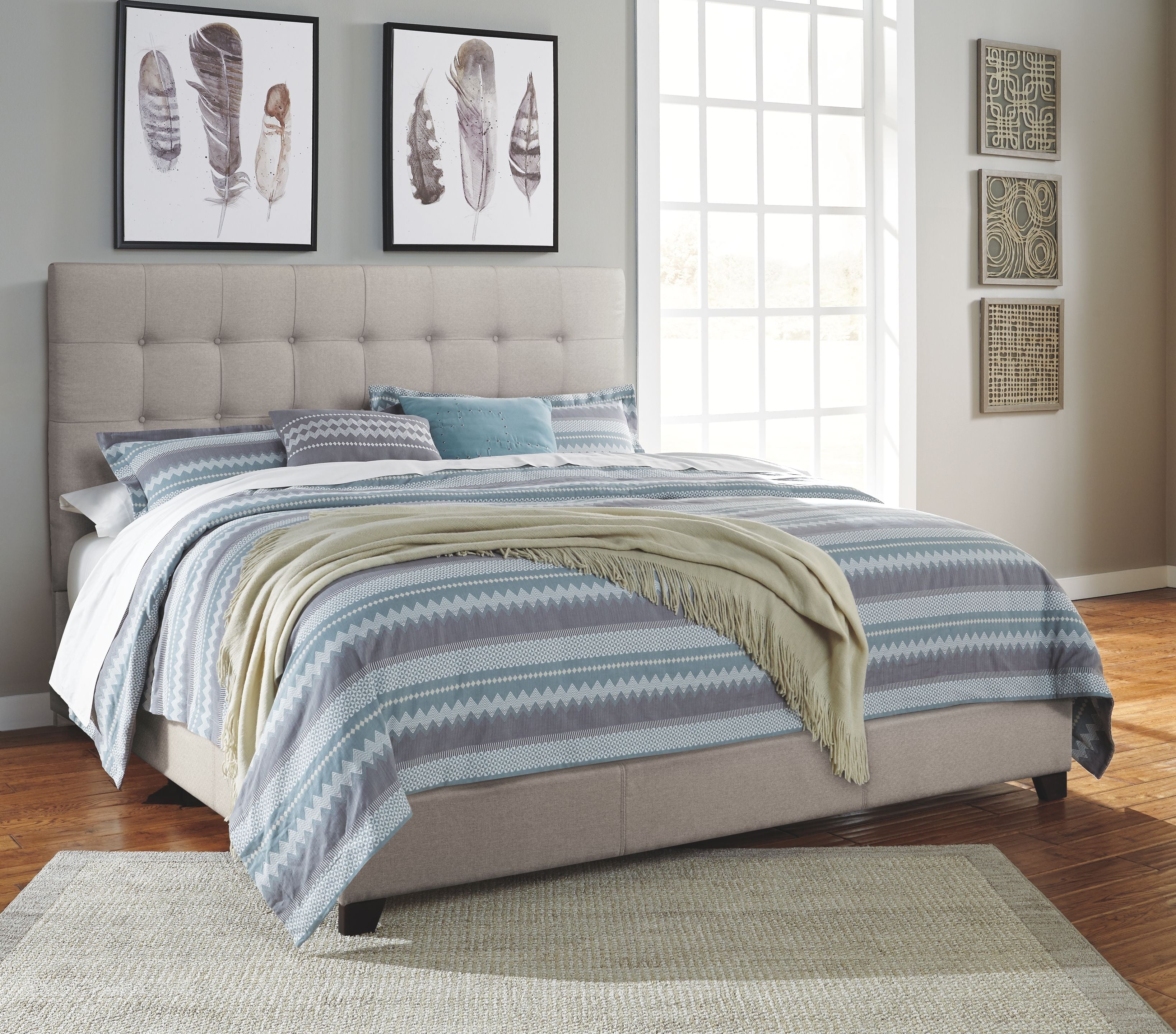 Dolante upholstered bed with beige tufted headboard, blue and white striped bedding, green throw