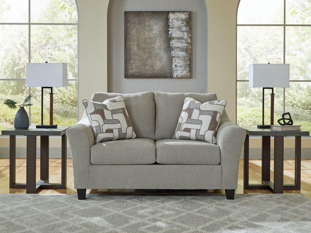 Taupe loveseat with rolled arms and two geometric throw pillows