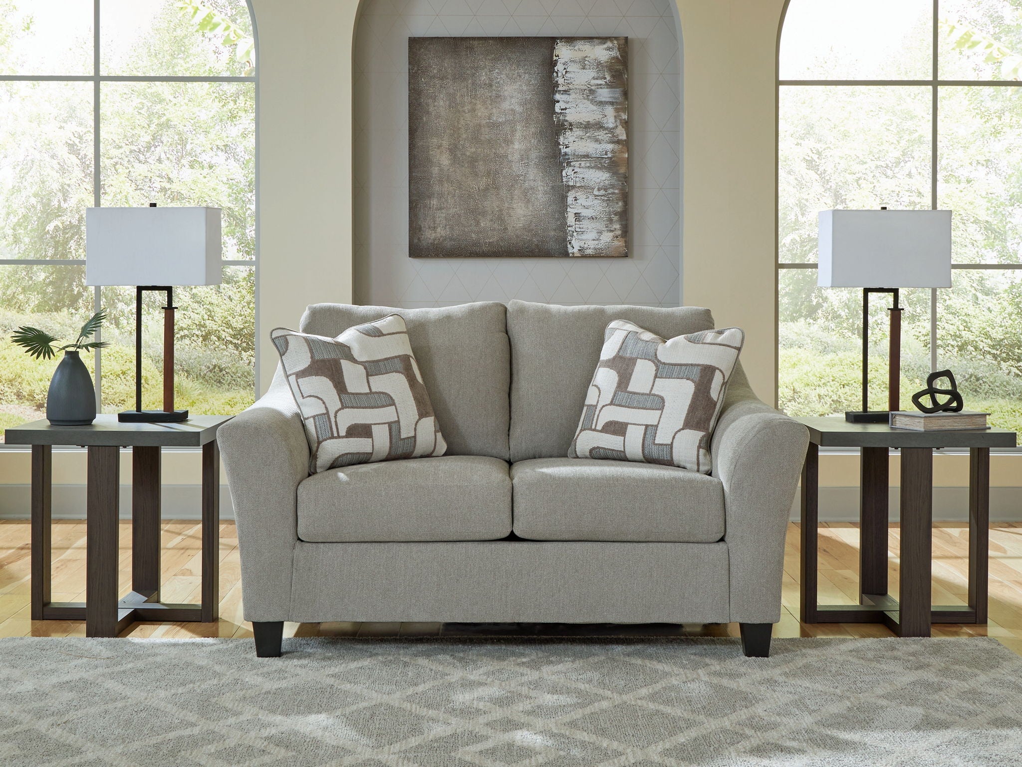 Taupe loveseat with rolled arms and two geometric throw pillows