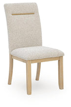 Light beige upholstered dining side chair with wooden legs and gold back bar