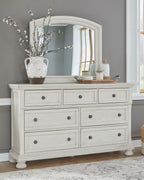 Antique white dresser with arched mirror, multiple drawers, dark metal knobs.