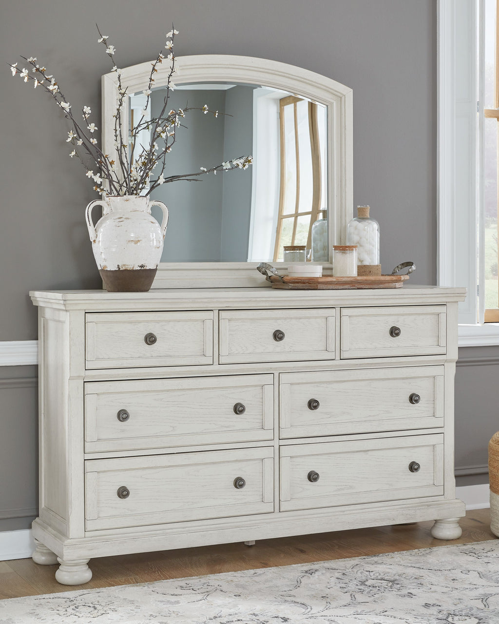White dresser with mirror and multiple drawer fronts, styled with decor on top