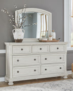 White dresser with mirror and multiple drawer fronts, styled with decor on top