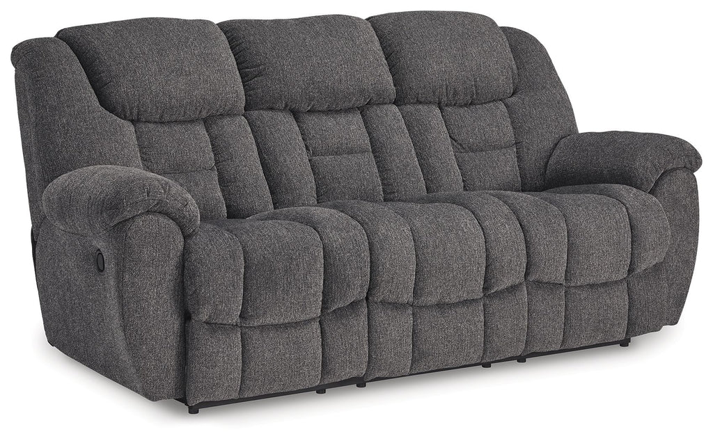 Charcoal gray reclining sofa with plush padded arms and tufted cushion panels