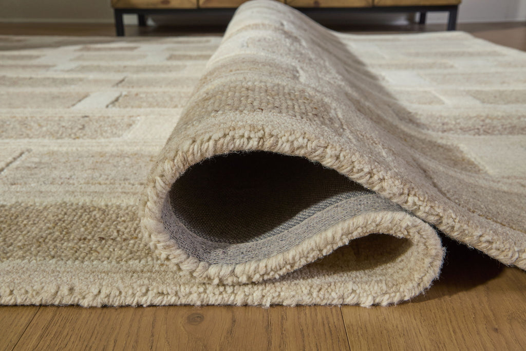 Beige rug corner with cut-pile edge and visible underside, folded for detail