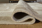 Beige rug corner with cut-pile edge and visible underside, folded for detail