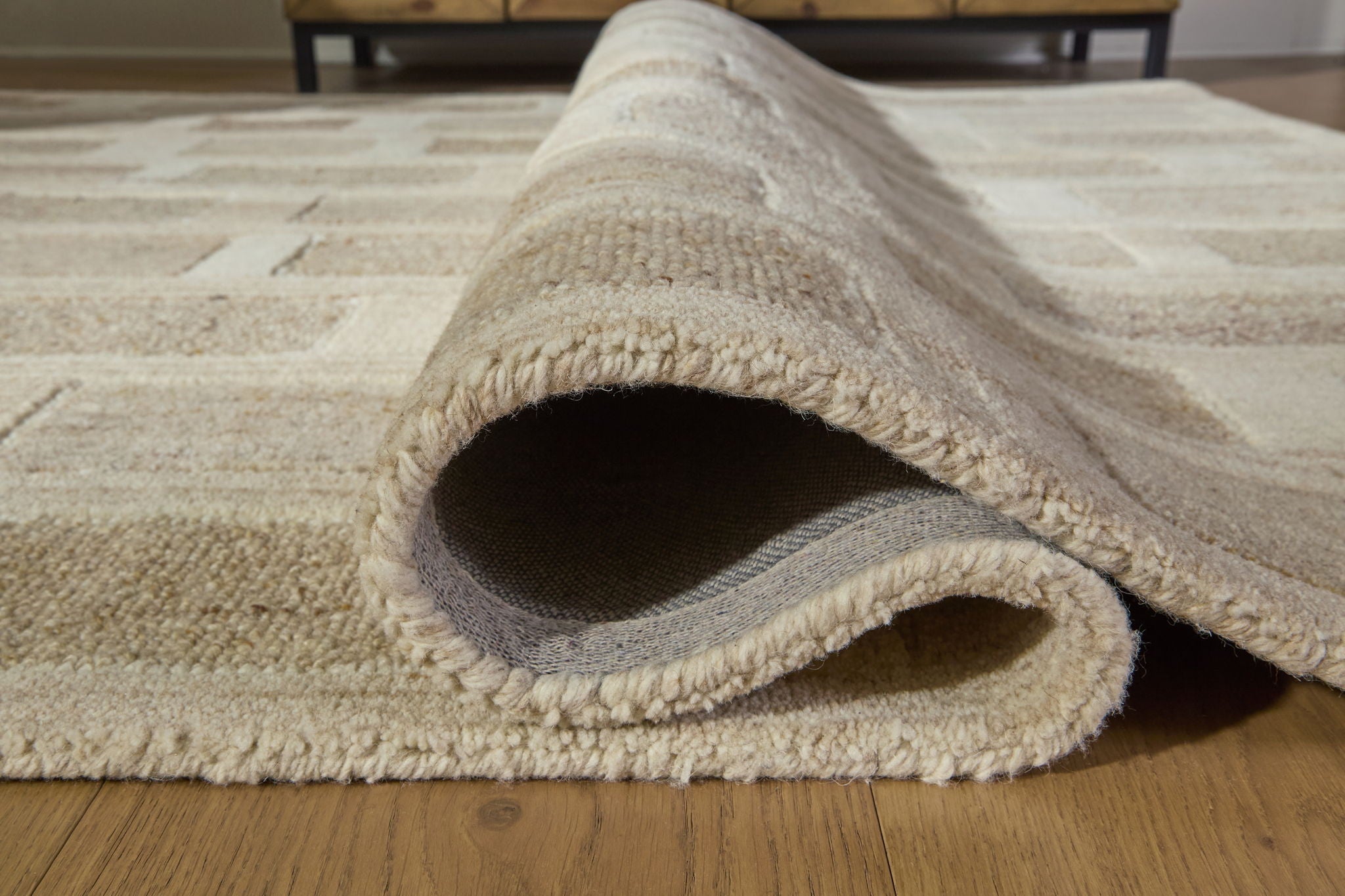 Beige rug corner with cut-pile edge and visible underside, folded for detail