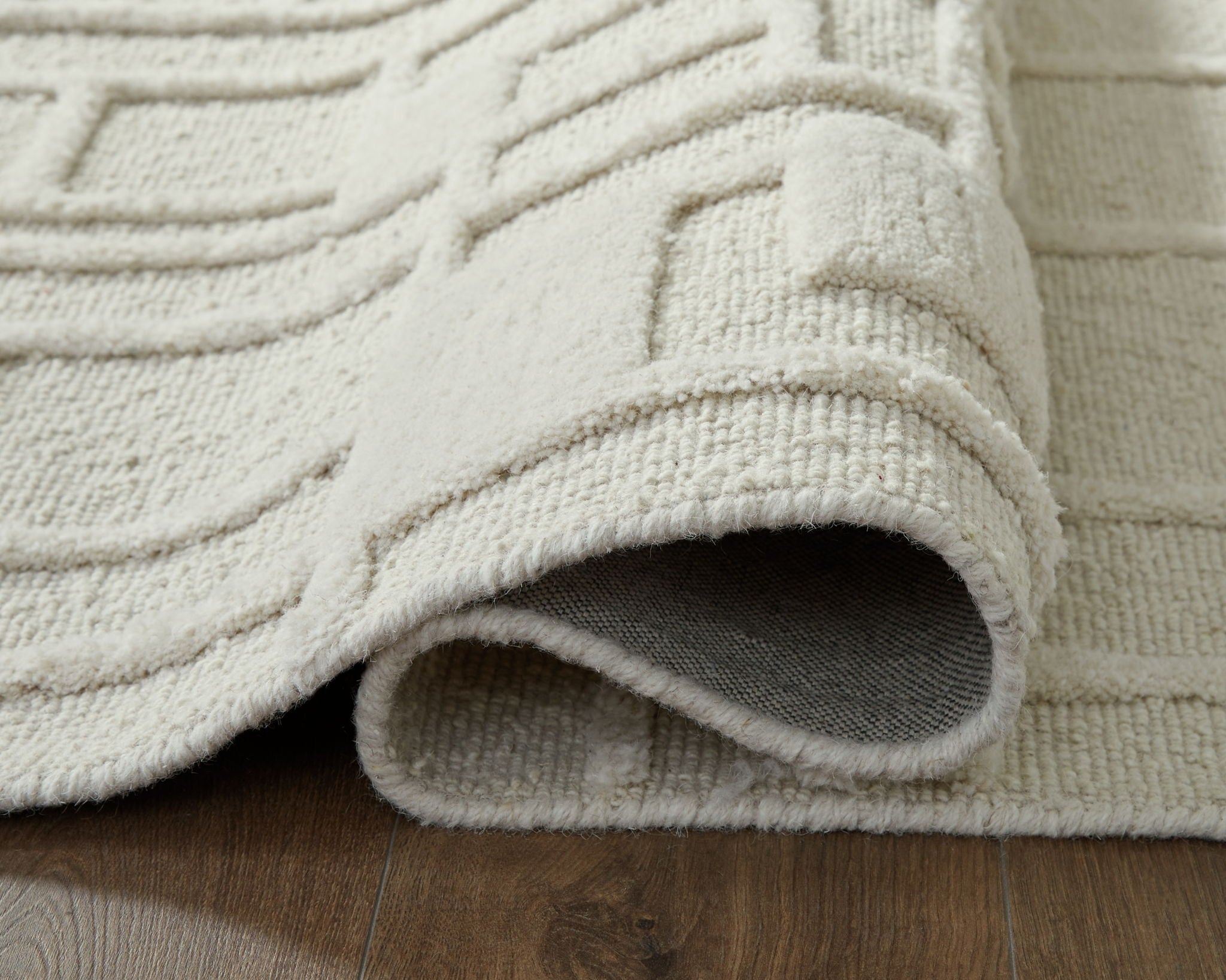 Empriss beige rug corner with rolled edge and cut-pile texture