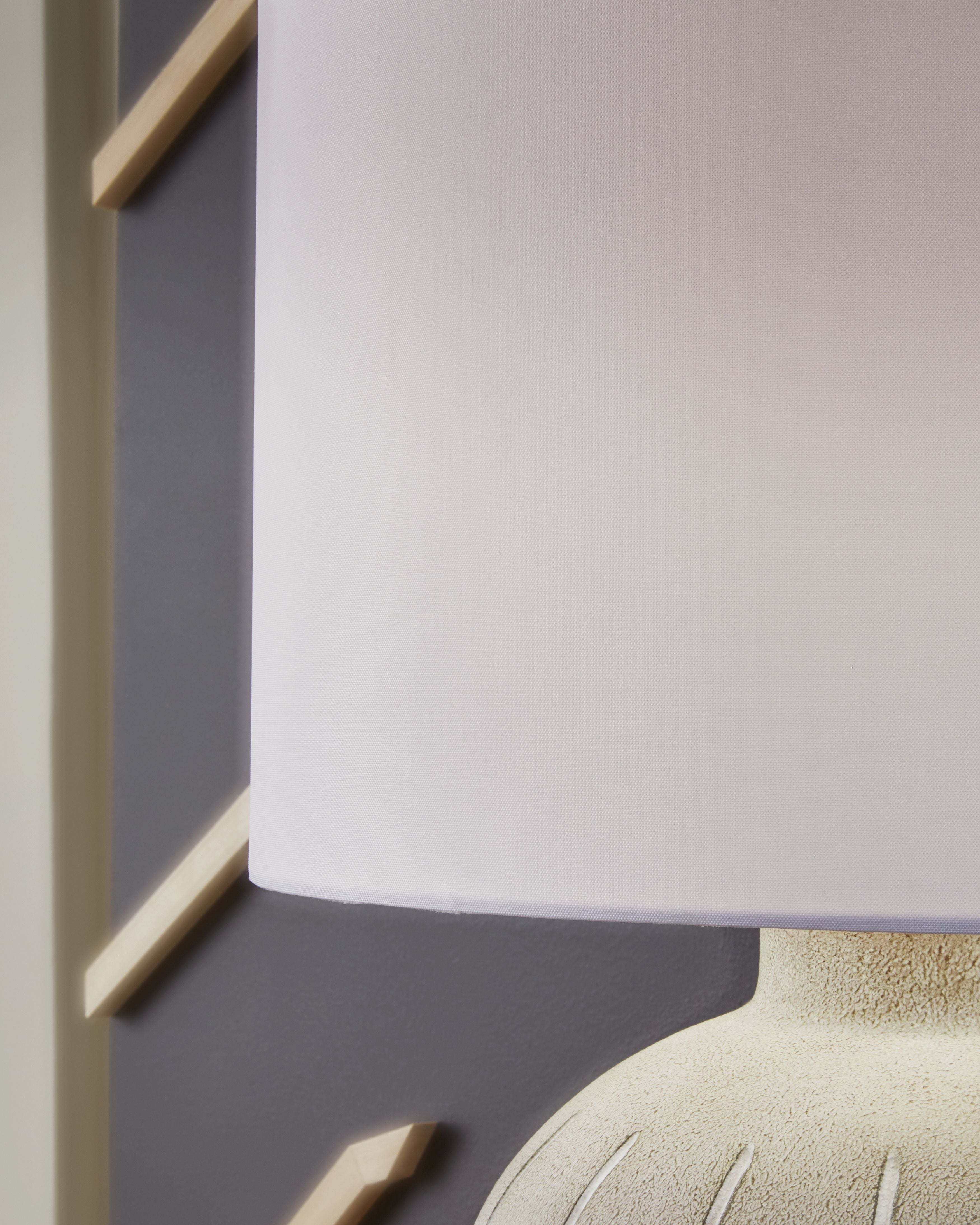 Warm gray ribbed poly table lamp base with white drum shade corner