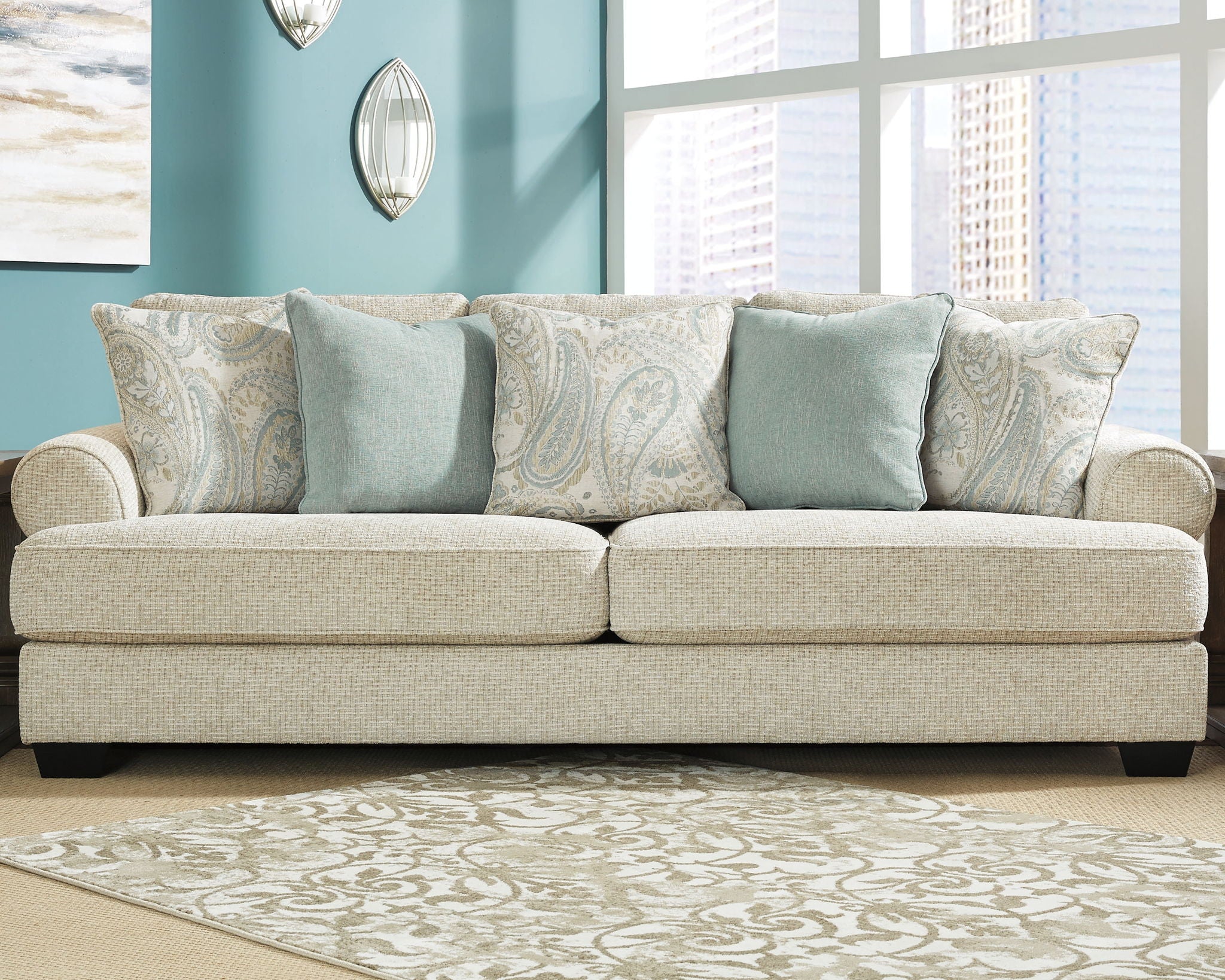 Upholstered sofa with light beige fabric and layered blue throw pillows