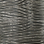 Close-up of ceramic vase with dark base and light wavy etched lines pattern.