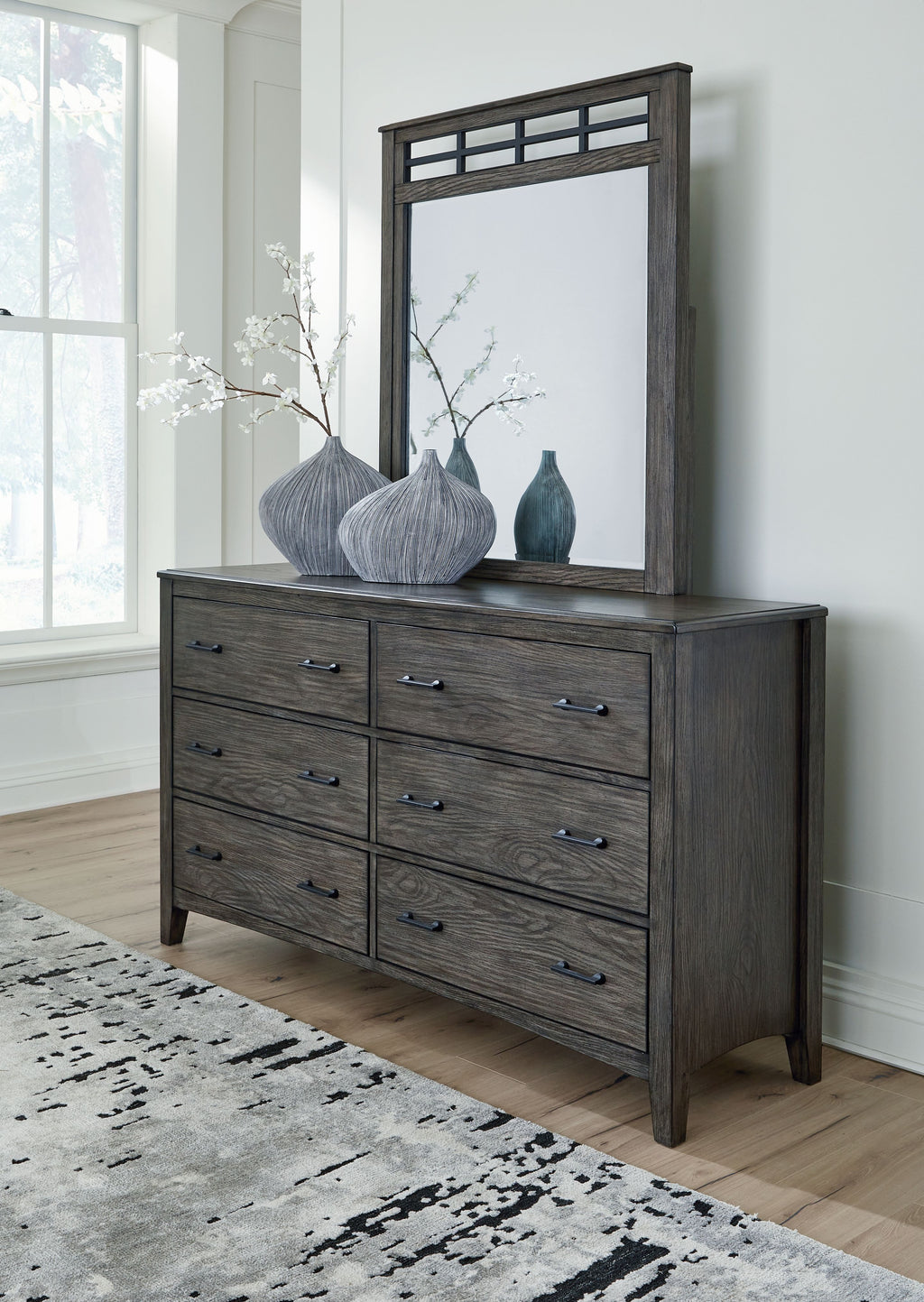 Grayish brown dresser with mirror frame and multiple drawers with metal pulls