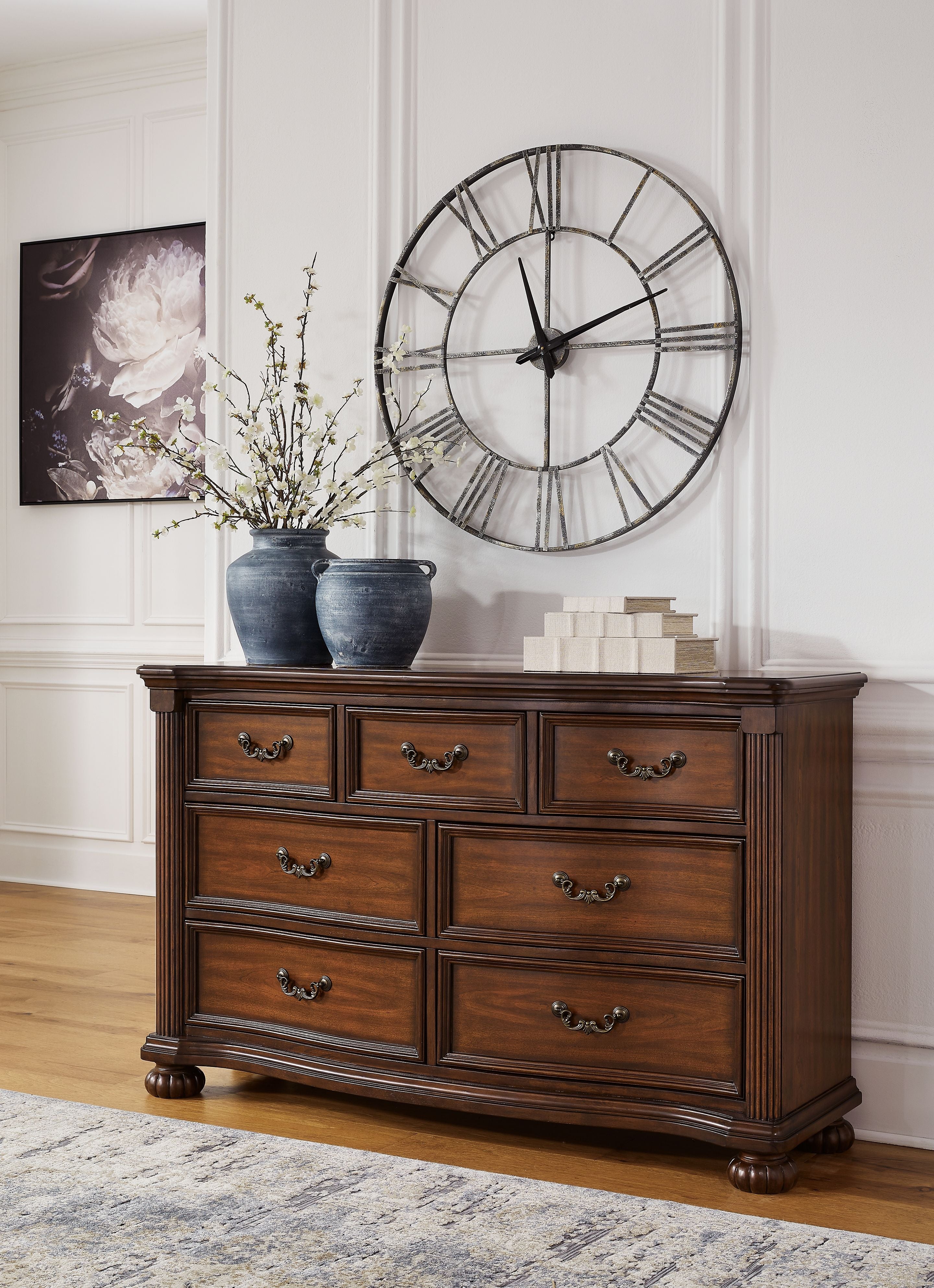 Brown wooden dresser with double rows of drawers and ornate metal pulls, tapered legs
