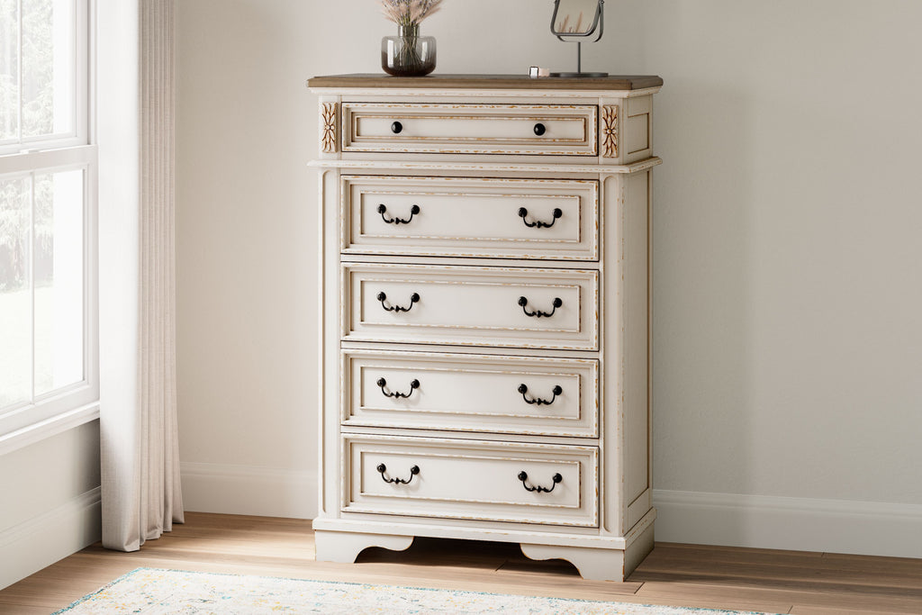 Distressed white five-drawer chest with ornate trim and dark metal pulls