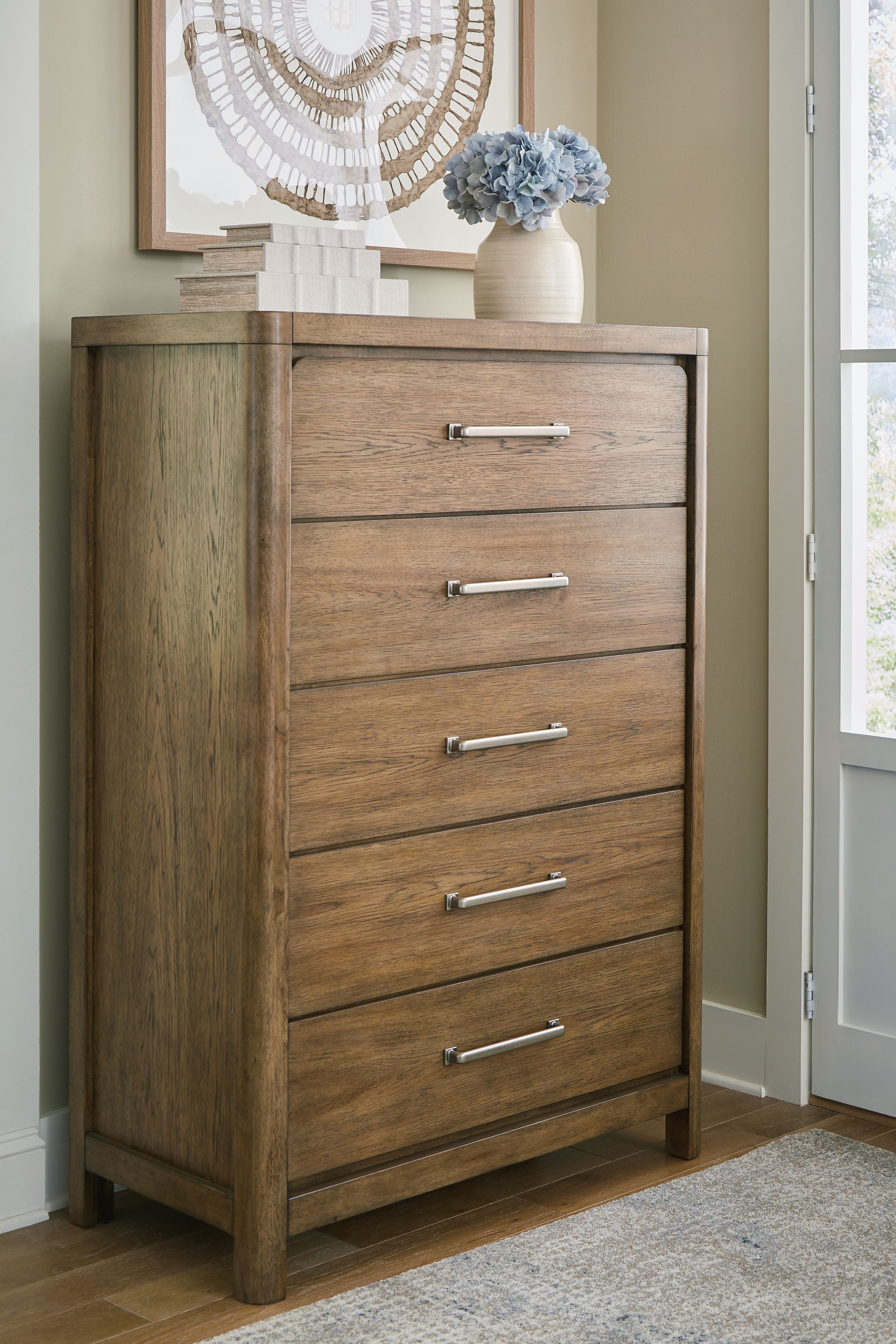 Light brown five-drawer chest with metal bar pulls and straight side panel