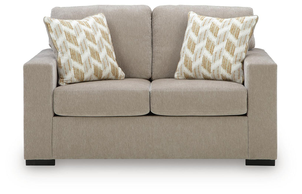 Beige-gray upholstered loveseat with two geometric accent pillows and low arms