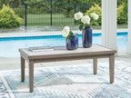 Rectangular cocktail table with light tabletop and brown wood legs on patio