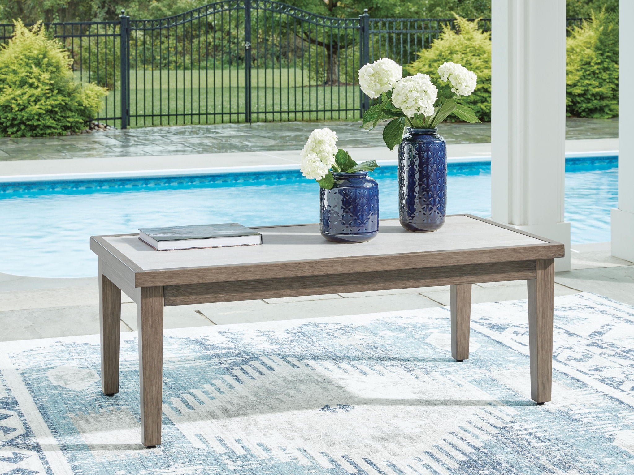Rectangular cocktail table with light tabletop and brown wood legs on patio