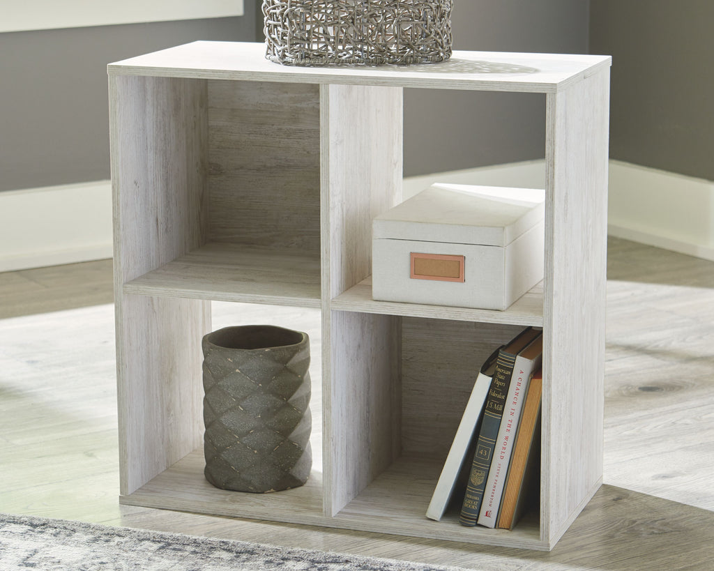 Whitewashed wood cube organizer with open cubbies for books and storage bins