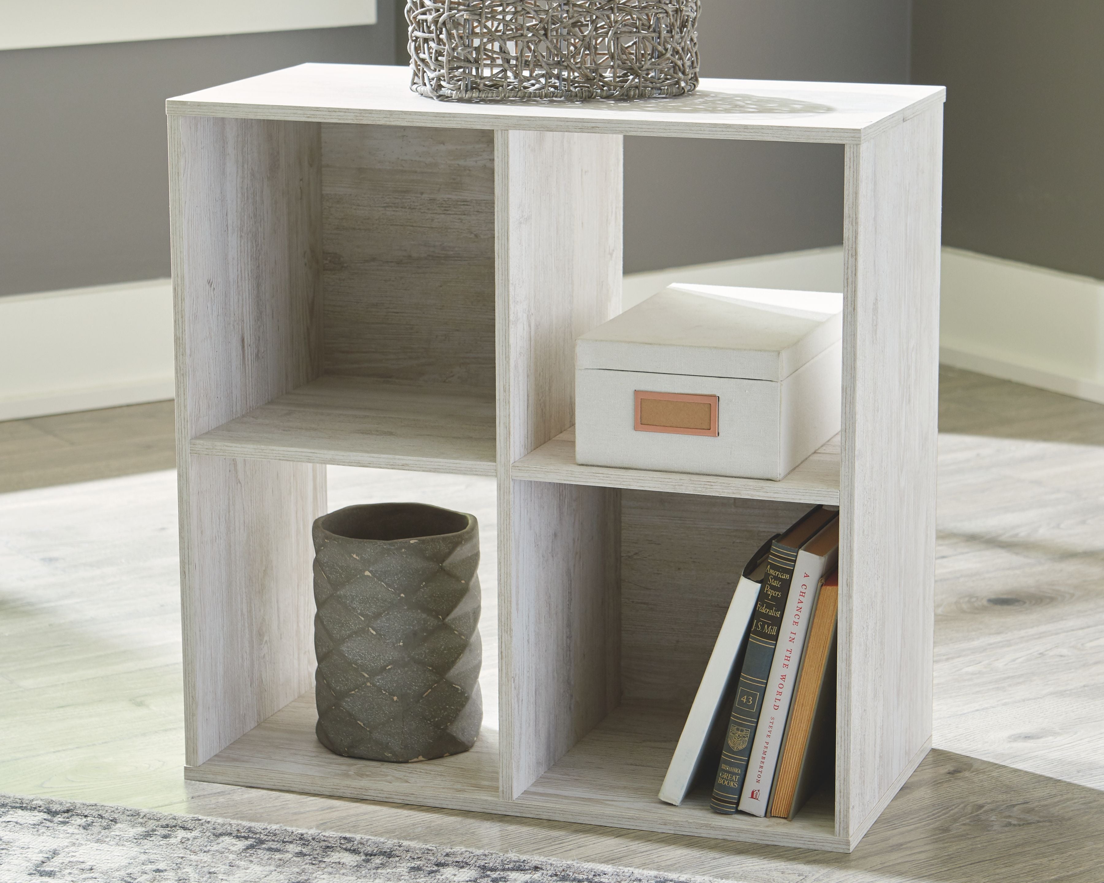 Whitewashed wood cube organizer with open cubbies for books and storage bins