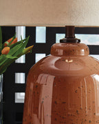 Rust glass table lamp with beige fabric shade and dark socket base