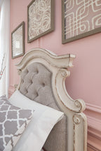 Tufted upholstered headboard panel with ornate white wood trim and beige fabric