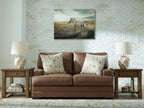Caramel-brown loveseat with two patterned throw pillows and square arms