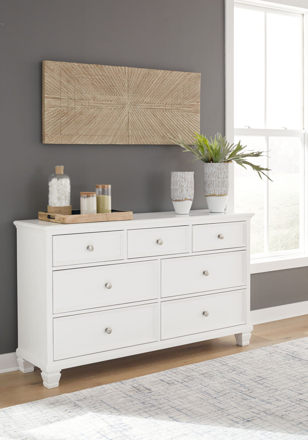 White dresser with drawers and round metal knobs, styled with vases