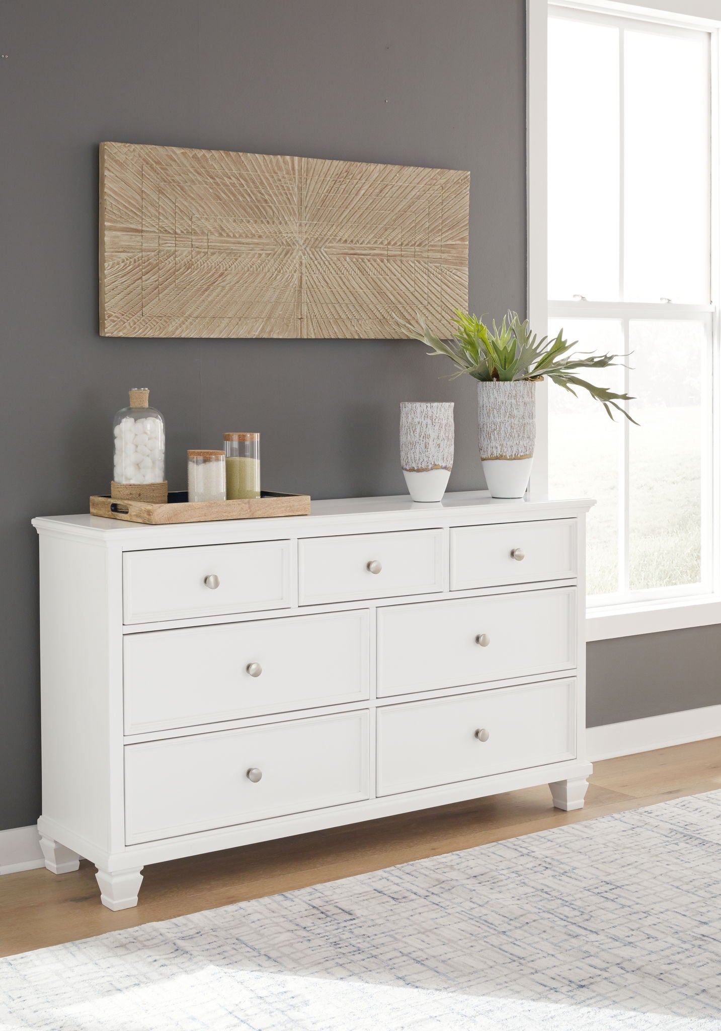 White dresser with drawers and round metal knobs, styled with vases