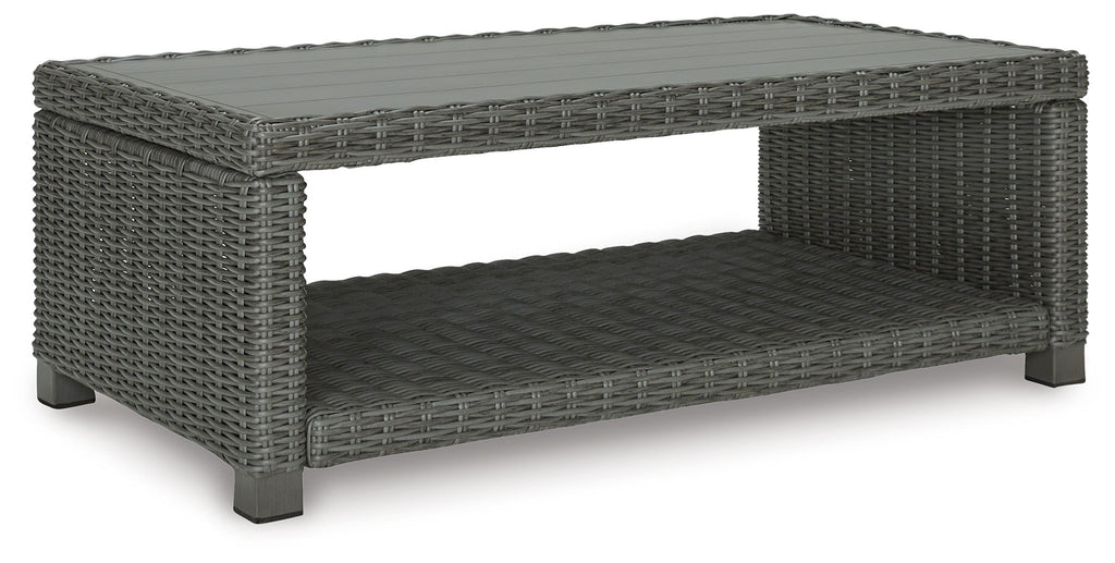 Gray rectangular cocktail table with woven frame and open-sided cushioned shelf