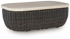 Beige rectangular cocktail table with dark brown wicker base and flat top