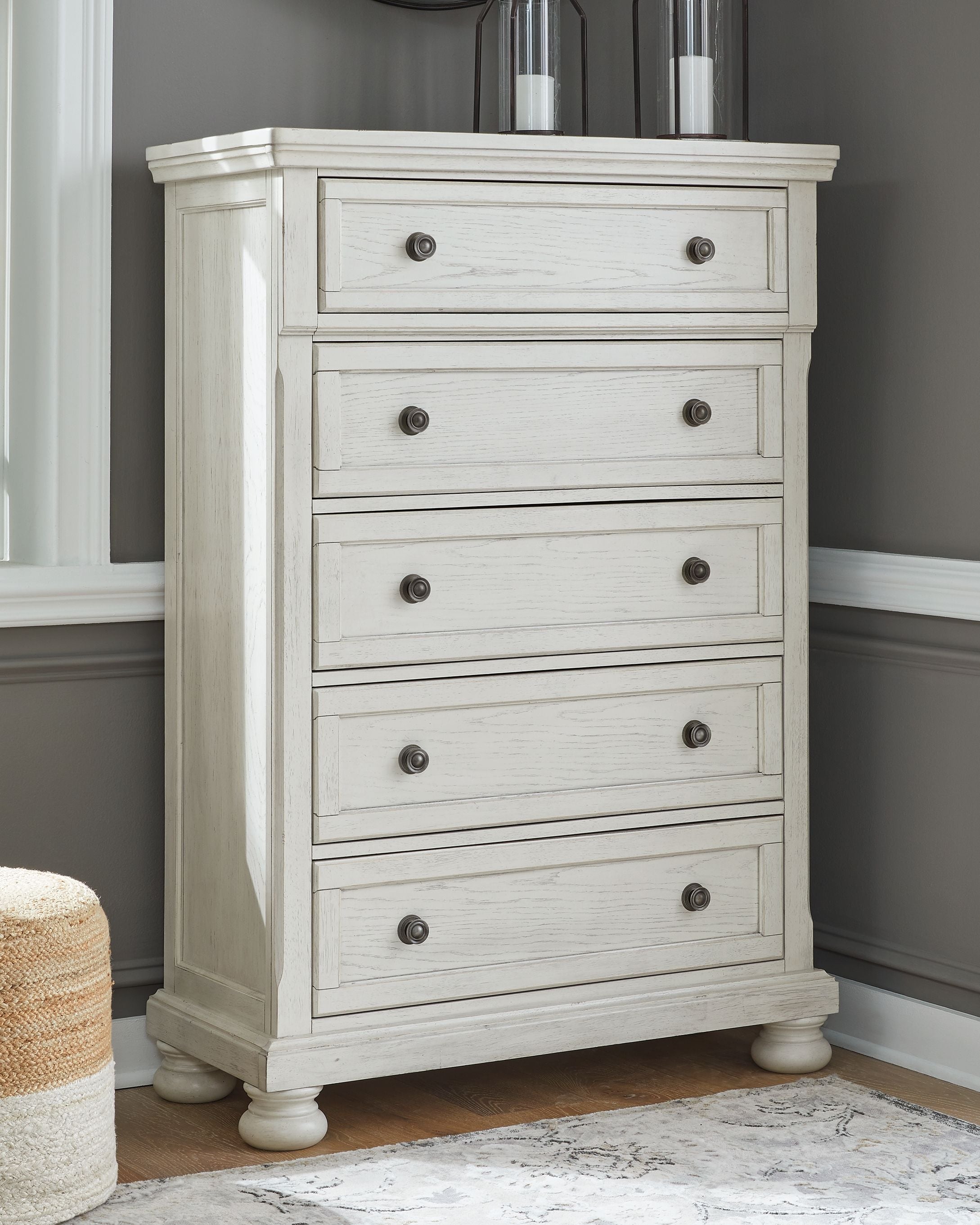 White tall chest of drawers with five drawer fronts and round metal knobs