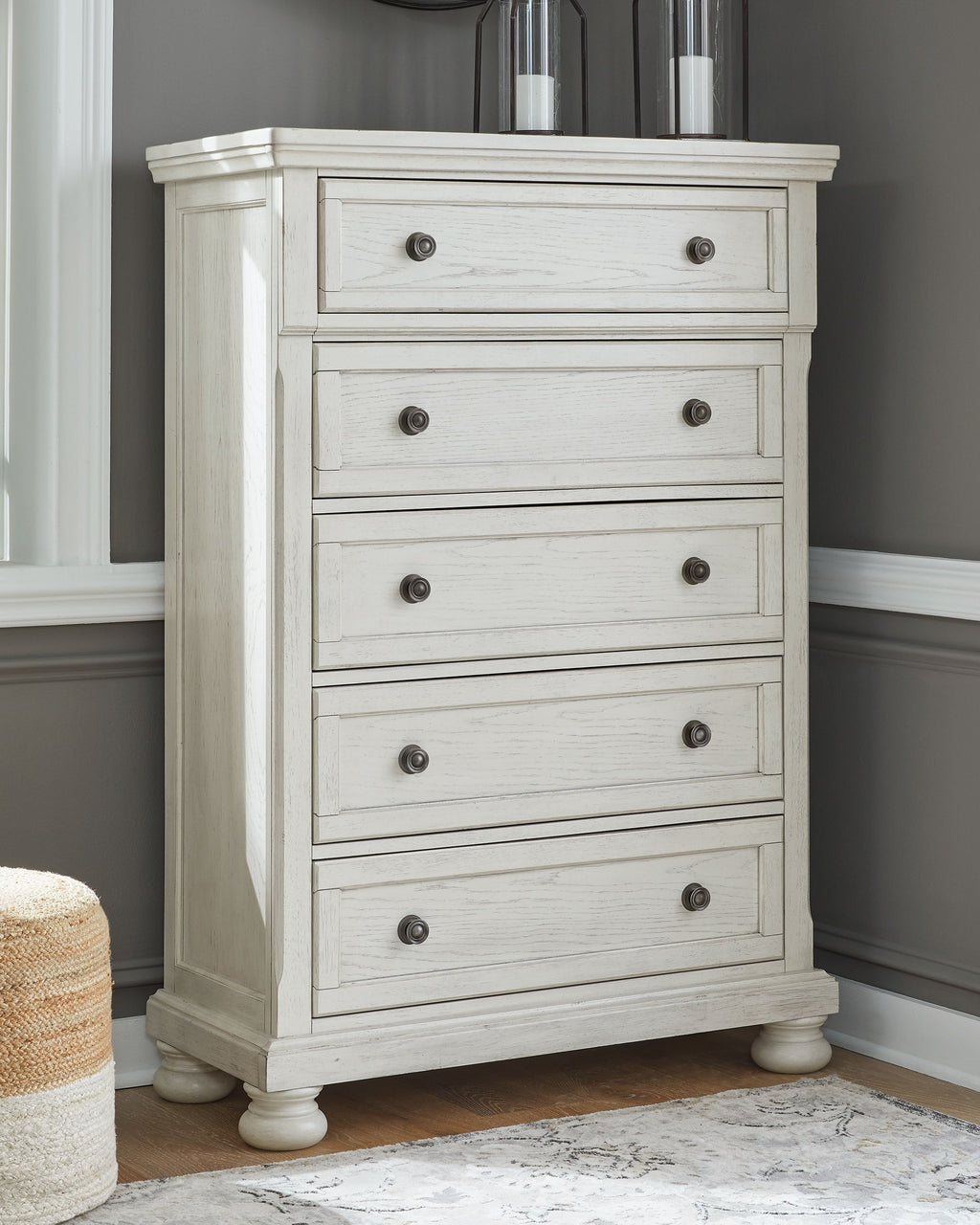 White chest of drawers with five stacked drawers and dark round knobs