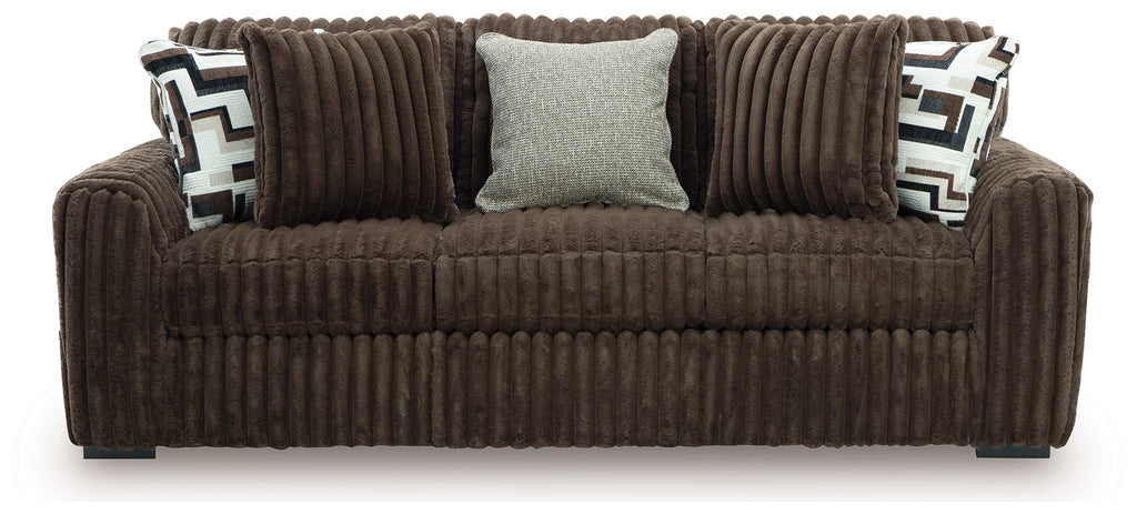 Dark brown corduroy sofa front view with two patterned pillows and three back cushions, light accent pillow