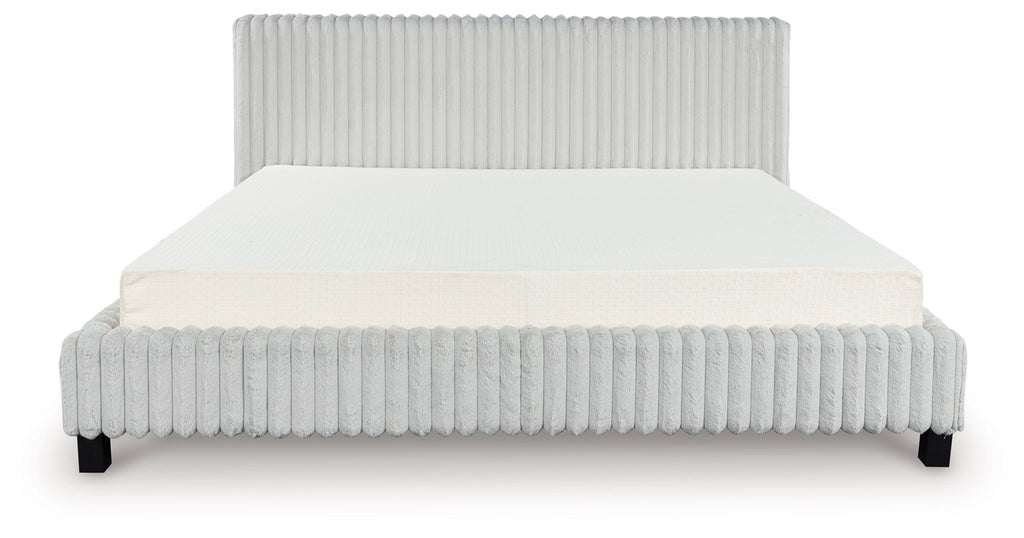 Upholstered bed with light ribbed headboard and sides, white mattress