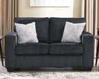 Dark gray loveseat with two white patterned throw pillows and padded square arms