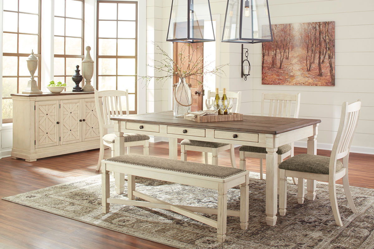 Rectangular dining table set with dark tabletop, upholstered bench, beige chairs, and server