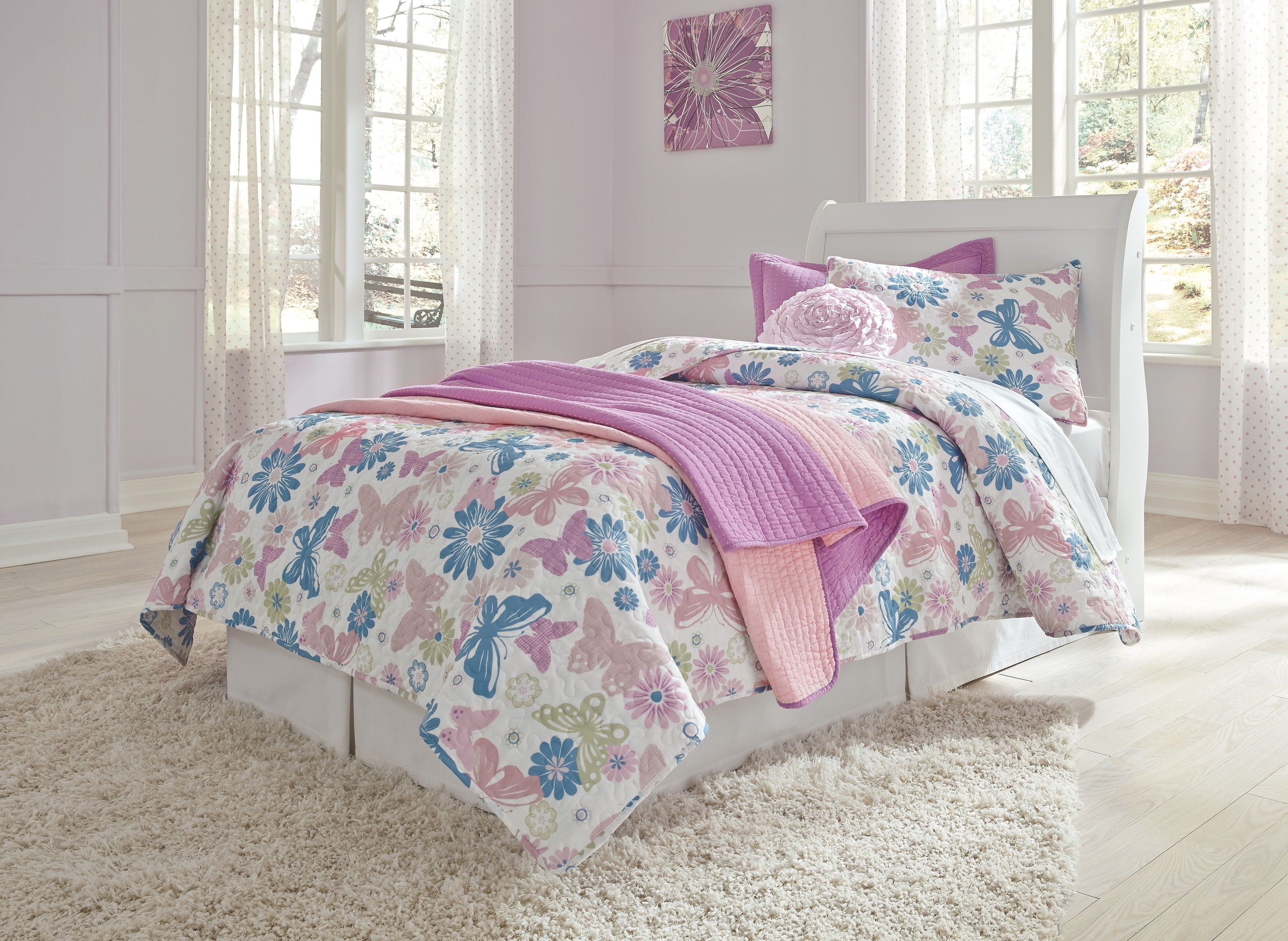 White sleigh bed headboard with floral comforter and purple-pink blankets
