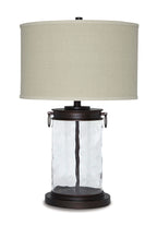 Table lamp with clear glass body, dark bronze finish base, and beige fabric shade